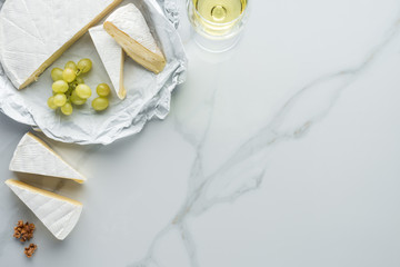 Wall Mural - flat lay with glass of wine, camembert cheese and grape on white marble surface