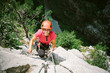 Young happy woman who is climbing along a via ferrata
