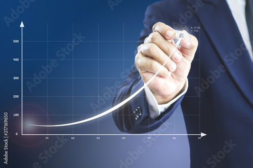 Cuadros en Lienzo Businessman drawing an exponential curve of a progress in business performance, return on investment - ROI, on a virtual screen presentation