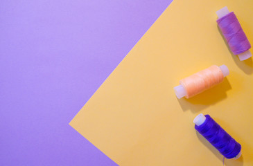 Pastel paper background with threads for design. Purple and yellow.