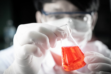 Student boy holding erlenmeyer flask chemistry equipment with red liquid benzene oil energy in school laboratory for testing. Scientist holding chemistry equipment.