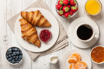 Breakfast with croissants, coffee, jams and berries