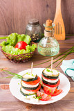 Fototapeta Nowy Jork - Original appetizer from fried zucchini, fresh tomatoes and feta cheese on a wooden skewer on a white plate