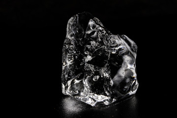 Ice on a black table. Melting piece of frozen water in a warm room.