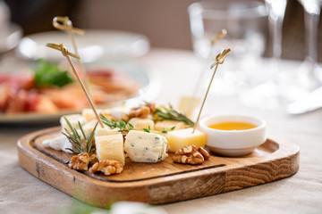 Cheese plate. Delicious cheese mix with walnuts, honey on wooden table. Tasting dish on a wooden plate. Food for wine.