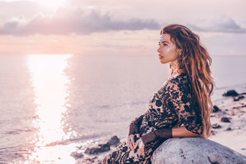 fashionable stylish woman with boho accessories on the beach at sunset