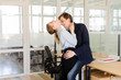 Young formal man and woman flirting and embracing with kiss in office having affair on work