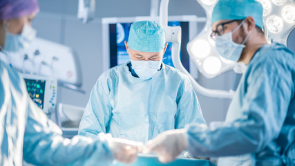 Wall Mural - Shot in the Operating Room, Assistant Hands out Instruments to Surgeons During Operation. Surgeons Perform Operation. Professional Medical Doctors Performing Surgery.