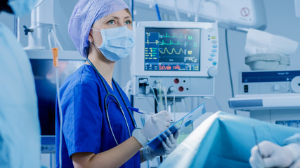 Wall Mural - In the Hospital Operating Room Anesthesiologist Looks and Monitors and Controls Patient's Vital Signs, Nodding to a Chief Surgeon to Proceed with Surgery.