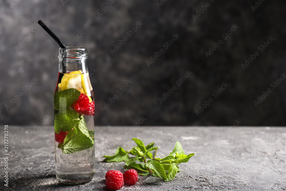 Glass bottle of fresh raspberry mojito on dark table