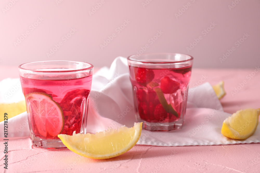 Glasses of fresh raspberry mojito on color table