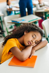 Wall Mural - tired african american schoolgirl sleeping on desk during lesson