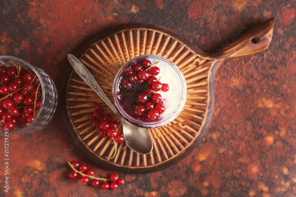 Glass jar with delicious rice pudding and currants on board