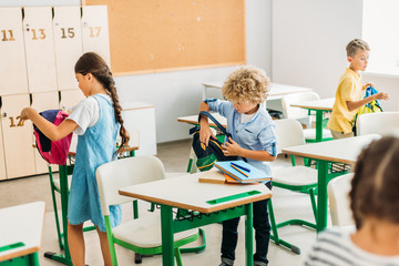 adorable schoolchildren preparing for lesson at classroom