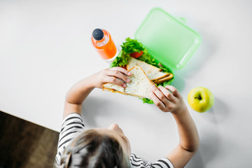 Wall Mural - top view of schoolgirl eating sandwich from lunch box