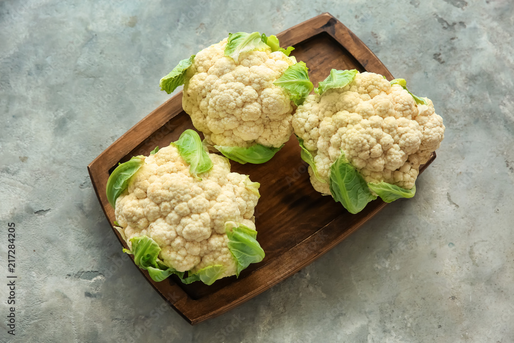Wooden board with fresh cauliflower on grey table