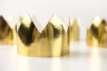 Cardboard Golden Crowns Lying On A White Table. Minimalistic Style.