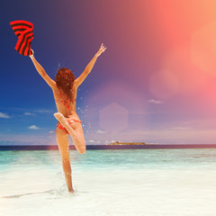 Wall Mural - Happy young woman jumping on the beach. Happy lifestyle. White sand, blue sky, sun and crystal sea of tropical beach. Vacation at Paradise. Ocean beach relax, travel to islands