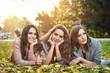 © dobok - three girlfriends lying on the grass in a park in autumn