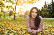 © dobok - young woman lying down on the ground in a park in autumn