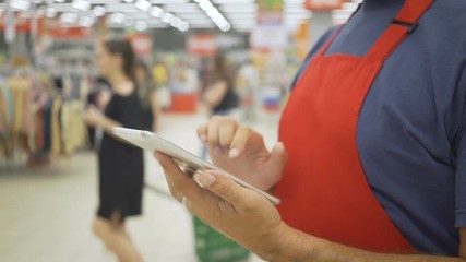 Salesperson using a digital tablet in supermarket