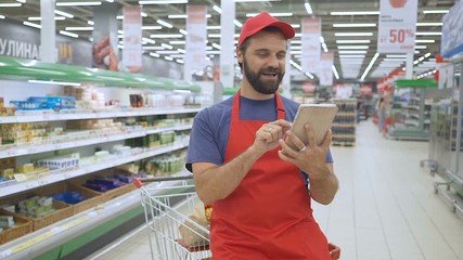 Funny sales clerk using a digital tablet in supermarket
