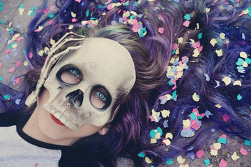 Chica joven celebrando halloween con una máscara de calavera