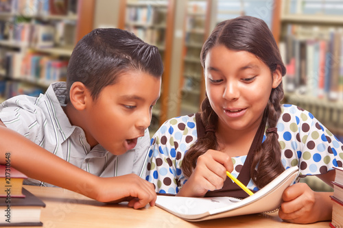Hispanic Boy and Girl Having Fun Studying Together In The Library