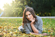 © dobok - young woman lying down on the ground in a park in autumn