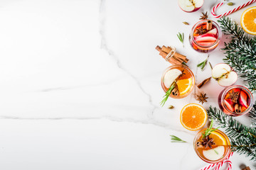 Traditional winter drinks, white and red mulled wine cocktail,  with white and red wine, spices, apple, orange. On white marble background copy space