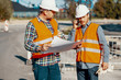 Worker and construction manager consulting project with engineer during road work