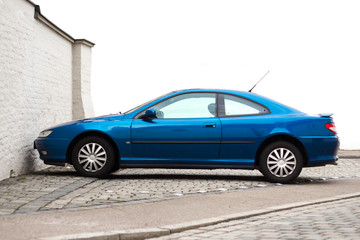 Blue dynamic sports car parked in front of a white wall