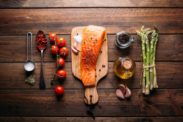 Recipe of salmon with various spices and vegetables on a rustic wooden background