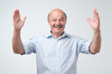 Poster - Handsome mature man gesturing with hands showing big and large size sign, measure symbol.