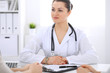 © rogerphoto - Brunette female doctor talking to patient at hospital office. Physician says about medical exams results for choosing optimal treatment. Healthcare and medicine concept