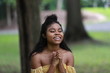© kosim - Smiling black woman praying emotionally
