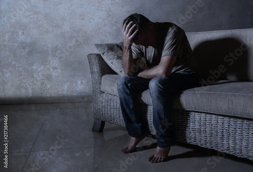 Fotografía lifestyle dramatic light portrait of young sad and depressed man sitting at shad