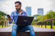 © Ranta Images - Young Handsome Indian Man In Park Using Laptop Computer And Mobile Phone