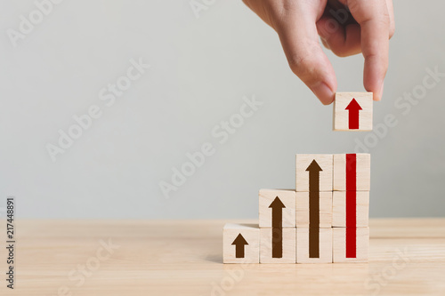 Fotografía Hand arranging wood block stacking as step stair with arrow up