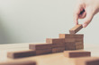 © Monster Ztudio - Hand arranging wood block stacking as step stair. Ladder career path concept for business growth success process