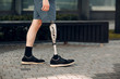 © primipil - Disabled young man with foot prosthesis walks along the street.