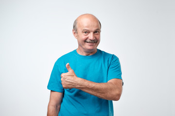 Wall Mural - Handsome, bald man with his thumb up in sign of optimism on white background