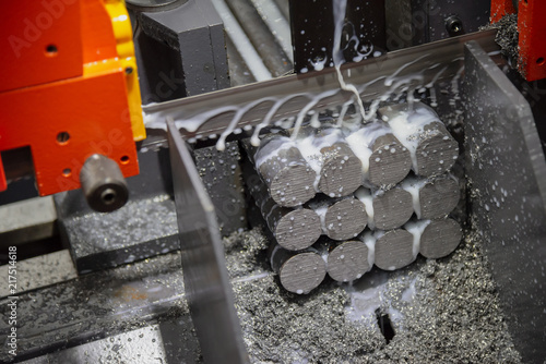 Fotografía The band saw machine cutting raw metals rods the with the coolant fluid