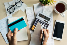 Young Woman Checking Bills, Taxes, Bank Account Balance And Calculating Credit Card Expenses At Home