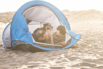 couple in outdoor free camping leisure activity have fun inside tiny home at the beach. Dog border collie behind them with love and friendship forever. bright colors and vacation family concept.