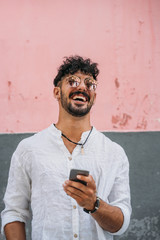 Outdoor portrait of handsome young hipster man with mobile phone.