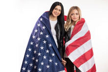 Awesome Beautiful Two Girls Are Wrapping Into The Merican Flag As They Like The USA. Closeup Portrait. Beauty And Country Concept