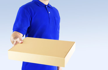 Delivery man in blue uniform and holding paper box with delivering package on gray background. Concept fast delivery service or order online shopping and express delivery.