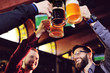 © Evgeniy Kalinovskiy - a group of young men's friends in a bar or pub drinking beer with glasses and watching football during the celebration of Oktoberfest