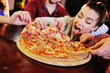 © Evgeniy Kalinovskiy - Appetizing hot pizza closeup on a table in the background of a group or company of people friends